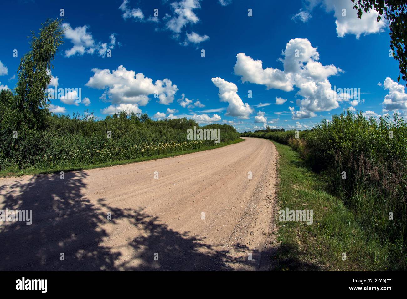 Beautiful summer time gravel road with clouds Stock Photo