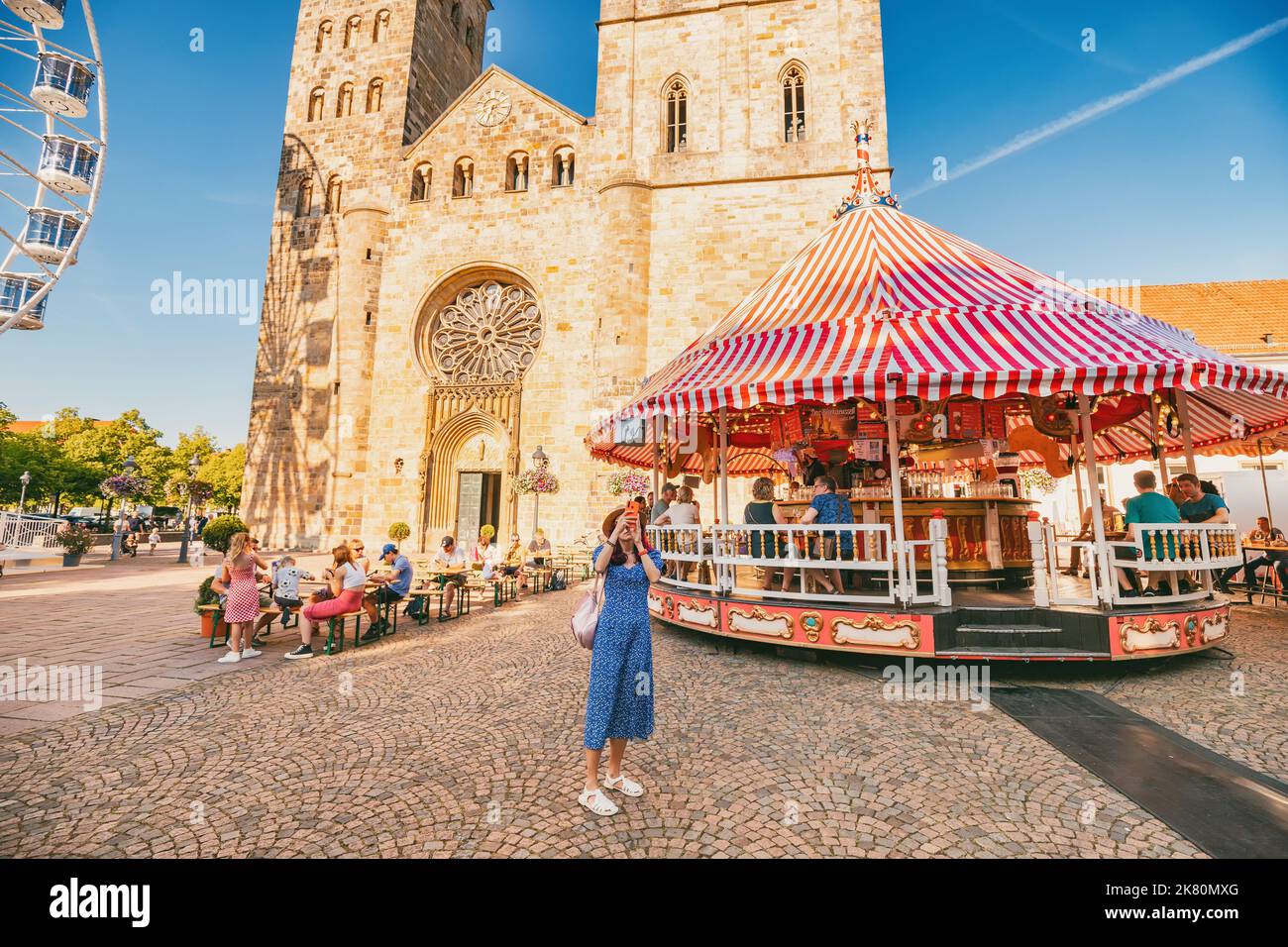 24 July 2022, Osnabruck, Germany: traveler girl takes a selfie photo for social networks at an amusement fair with a Ferris wheel in the old European Stock Photo