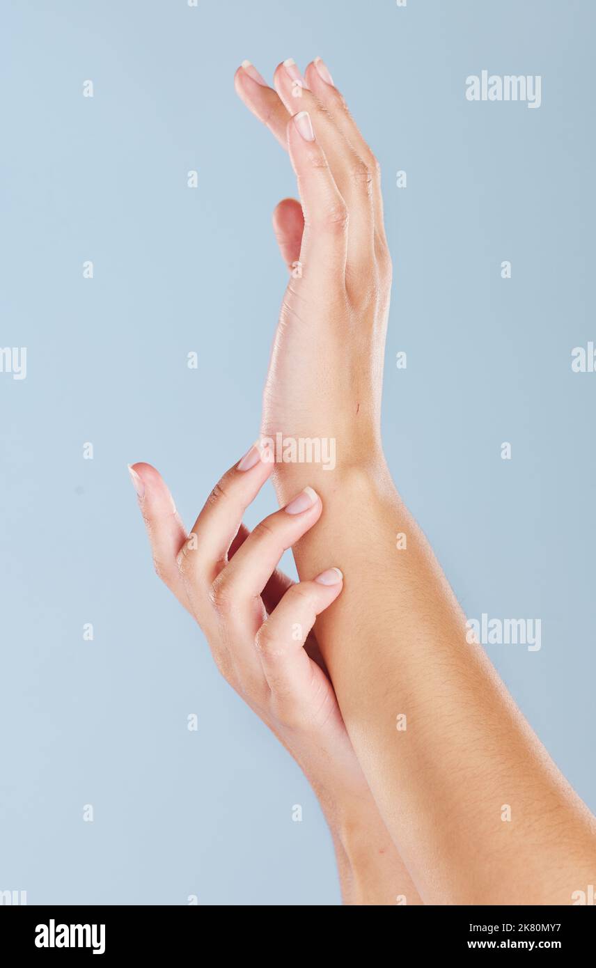 Beauty, skincare and spa with hands of woman for manicure, wellness or health cream massage against blue background in studio. Luxury, cosmetics and Stock Photo