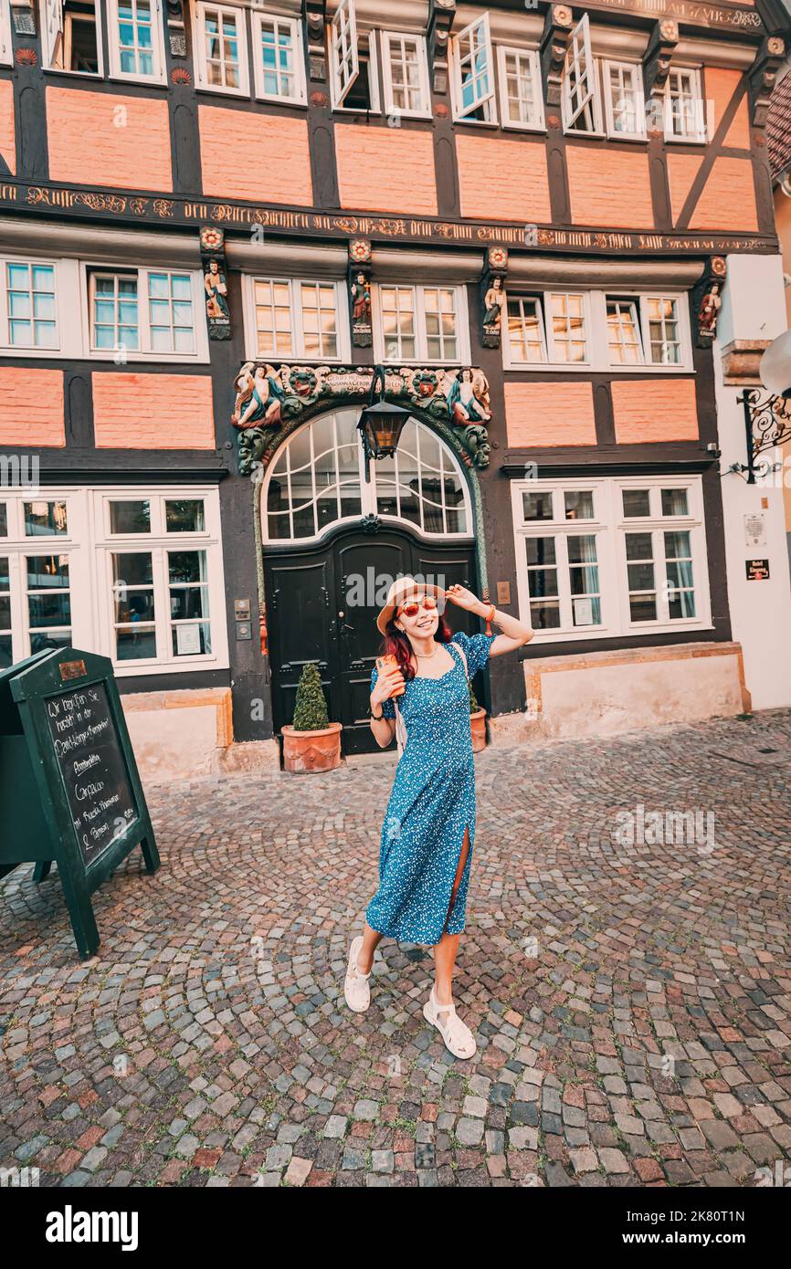 24 July 2022, Osnabruck, Germany: Tourist girl at the entrance to Hotel situated in a half timbered architecture in the center of the old town of Osna Stock Photo