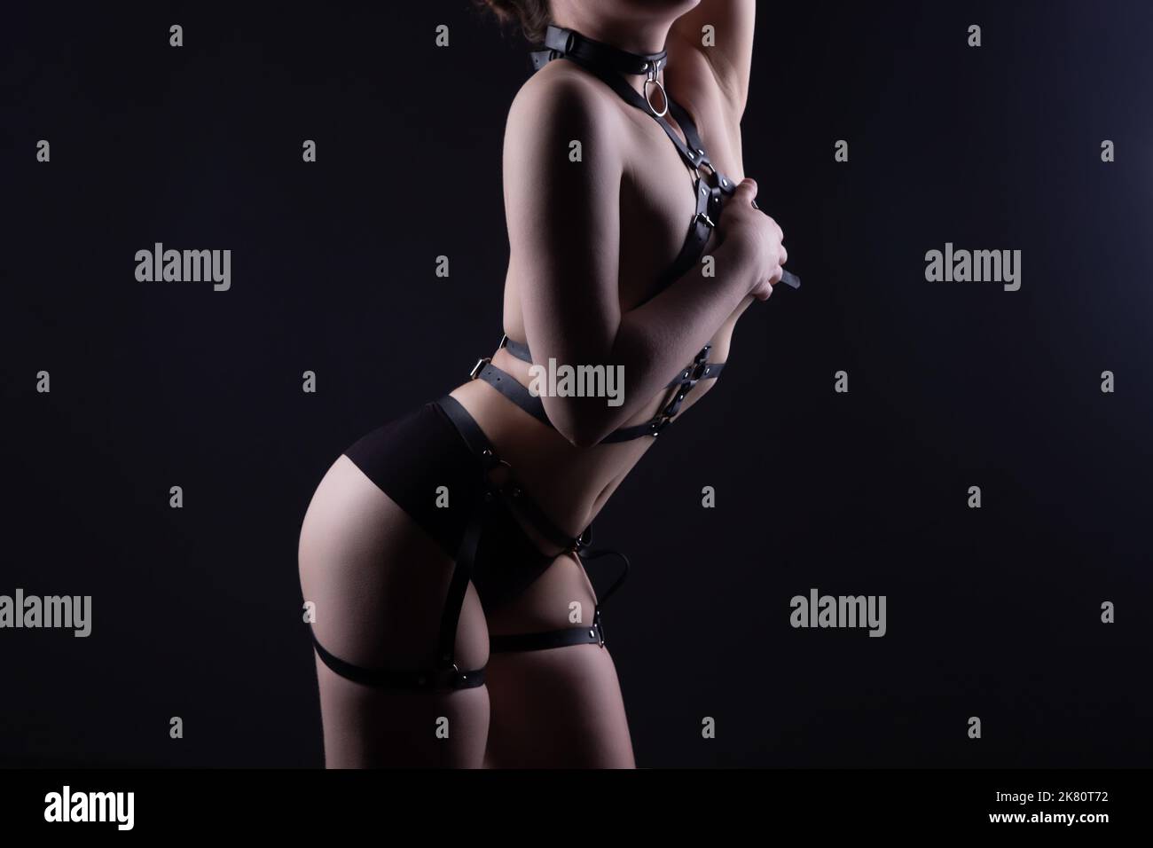 Image of woman covered breast in black bdsm belt Stock Photo