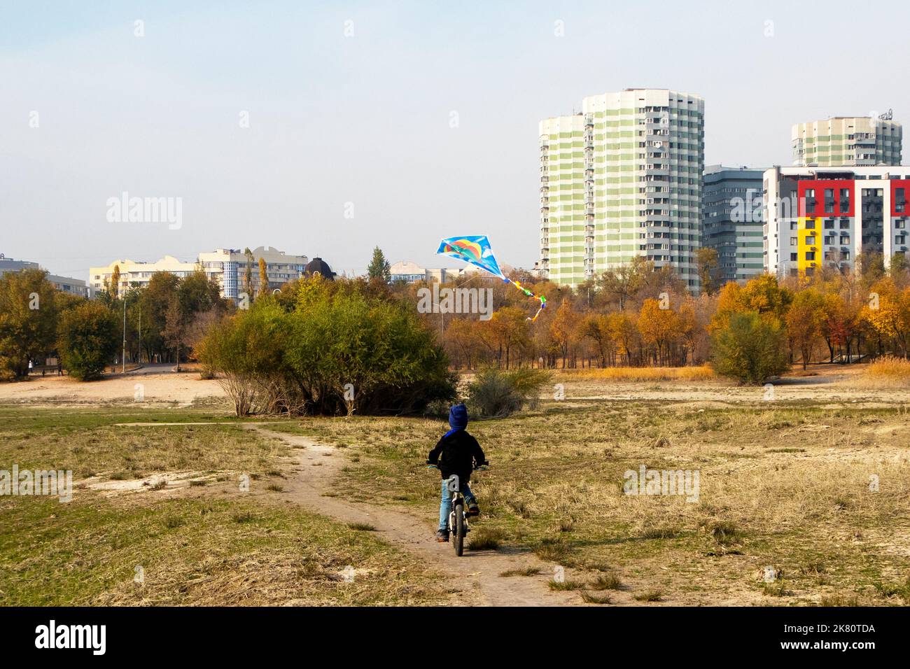 a boy rides a bicycle with a kite Stock Photo