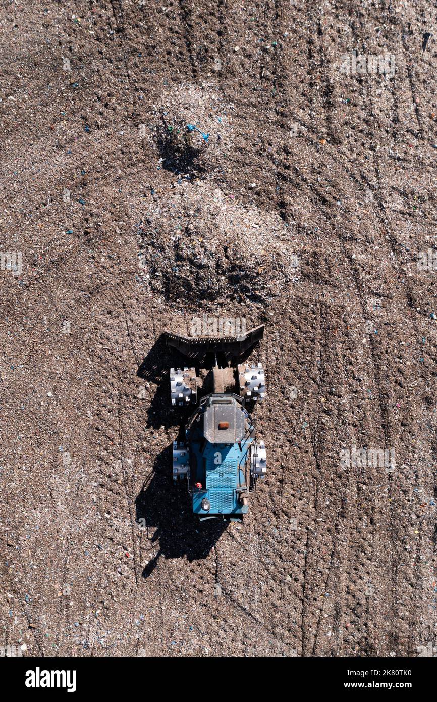 Aerial view directly above a  Bulldozer machine moving waste and household garbage on a large landfill heap with copy space Stock Photo
