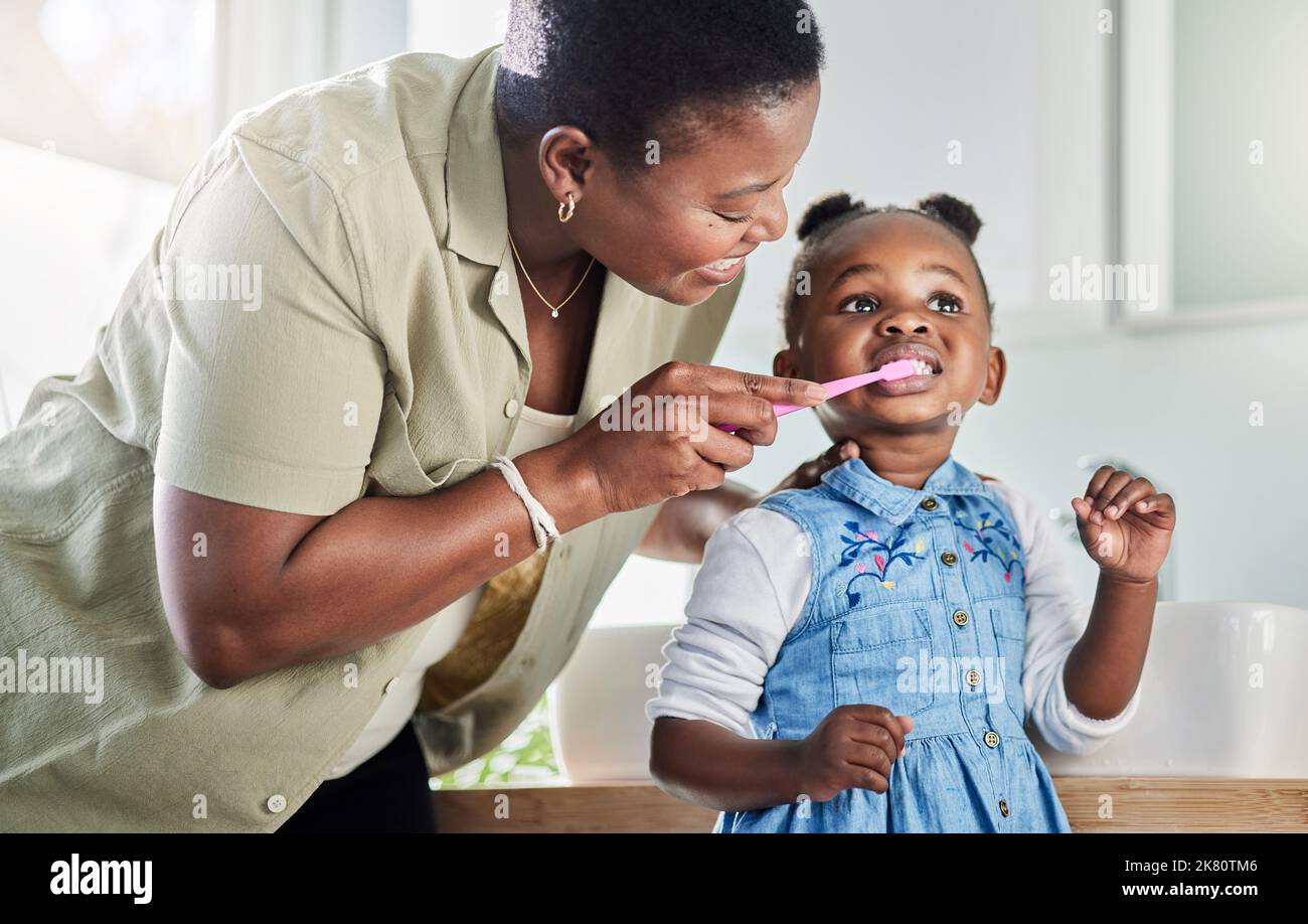 Brushing them well to prevent cavities and infection. a mother brushing