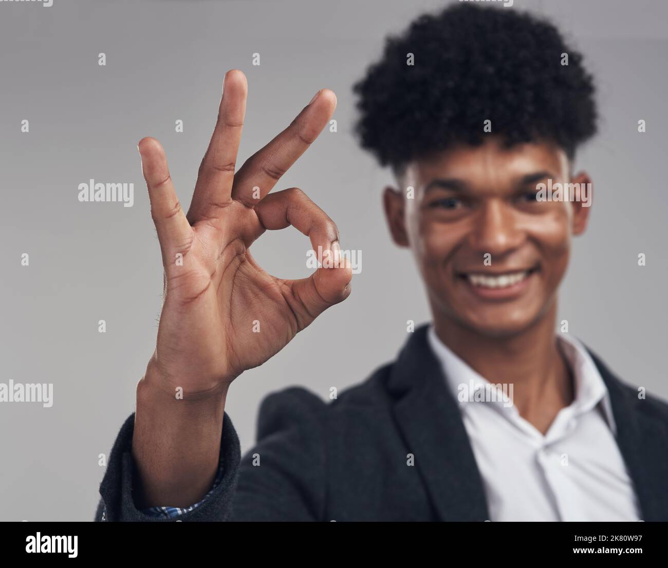 I dont double profit, I triple it. Studio shot of a young businessman showing an okay hand gesture against a grey background. Stock Photo