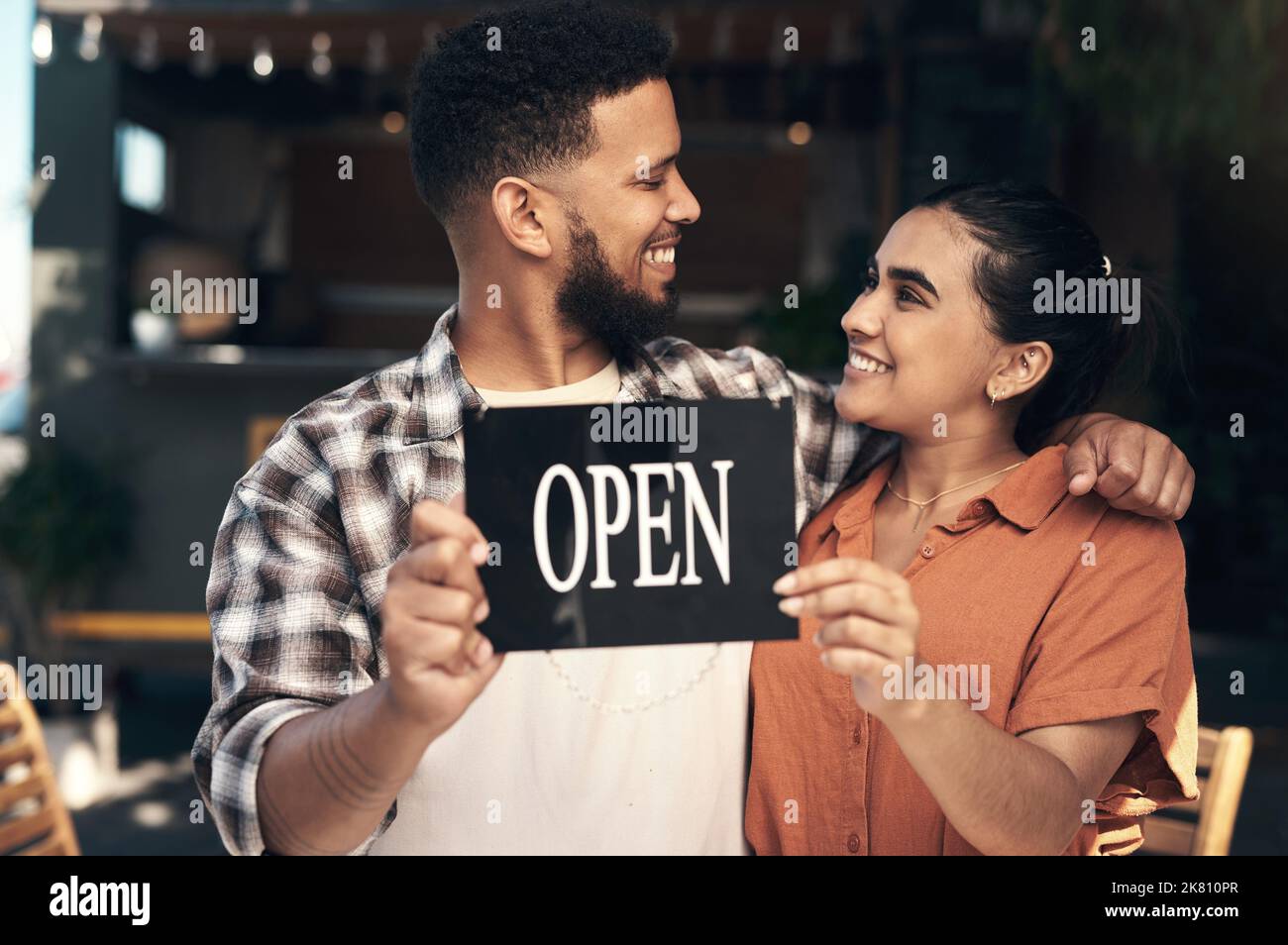 We did it. two young restaurant owners standing outside together and holding an open sign. Stock Photo