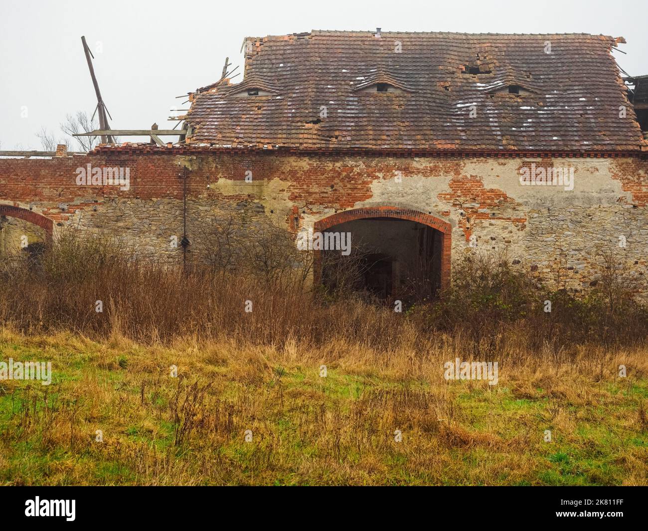old abandoned farm barn with destroyed roof in a village in a moody misty overcast day, front view Stock Photo