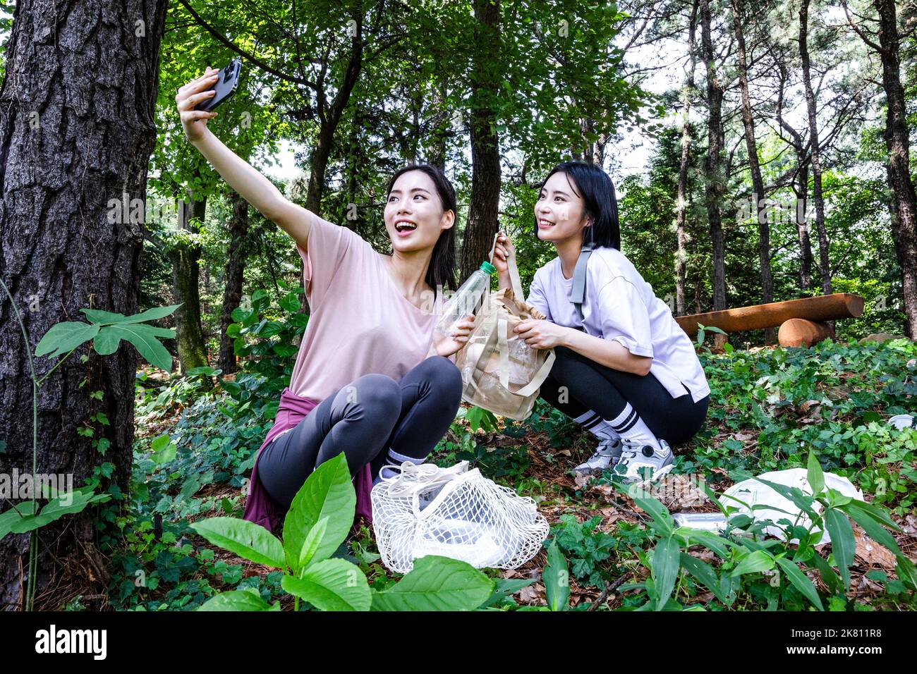 korean young women hiking and plogging picking up litter, garbage with taking photo Stock Photo