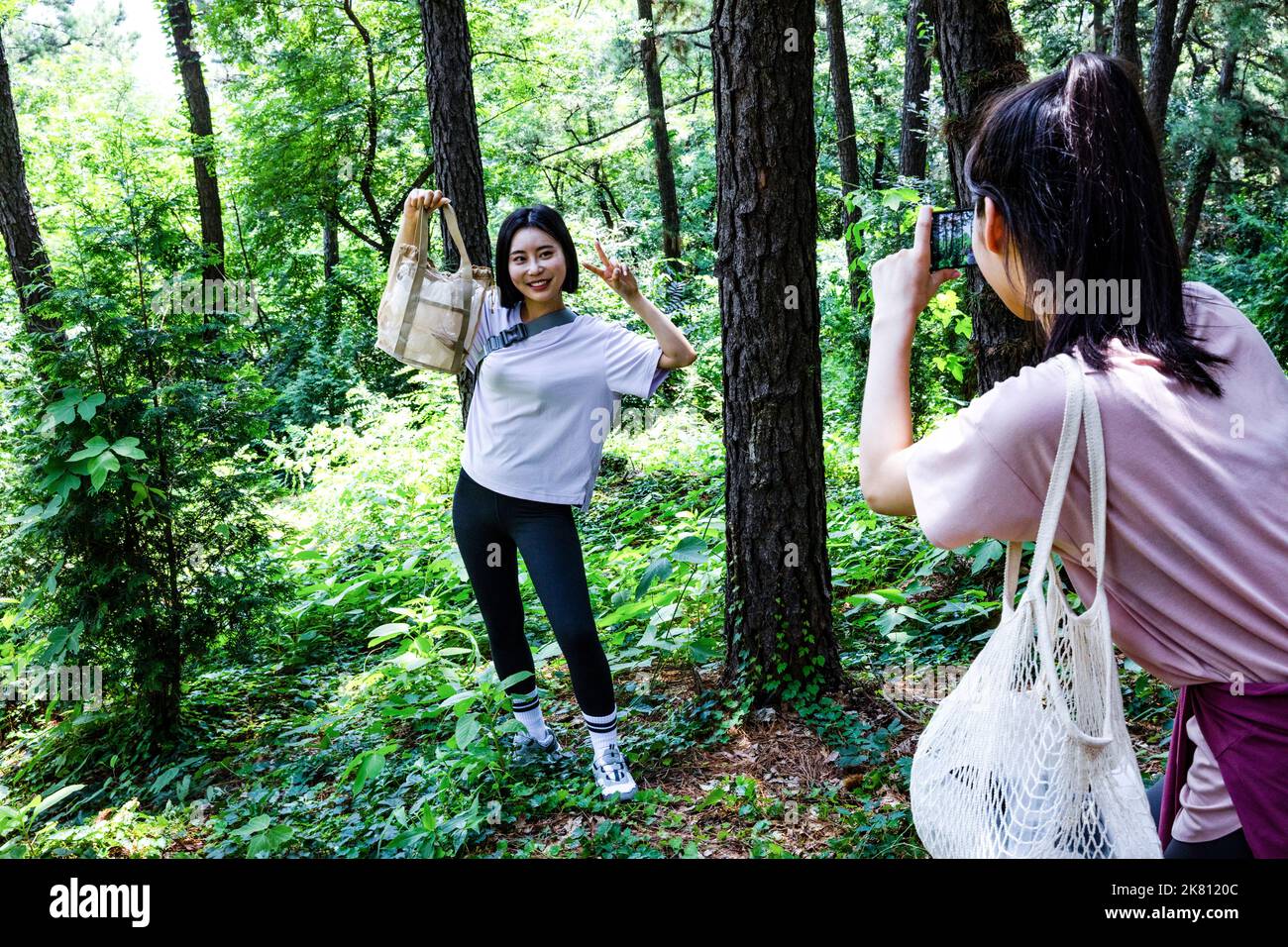 korean young woman hiking and plogging picking up litter, garbage with
