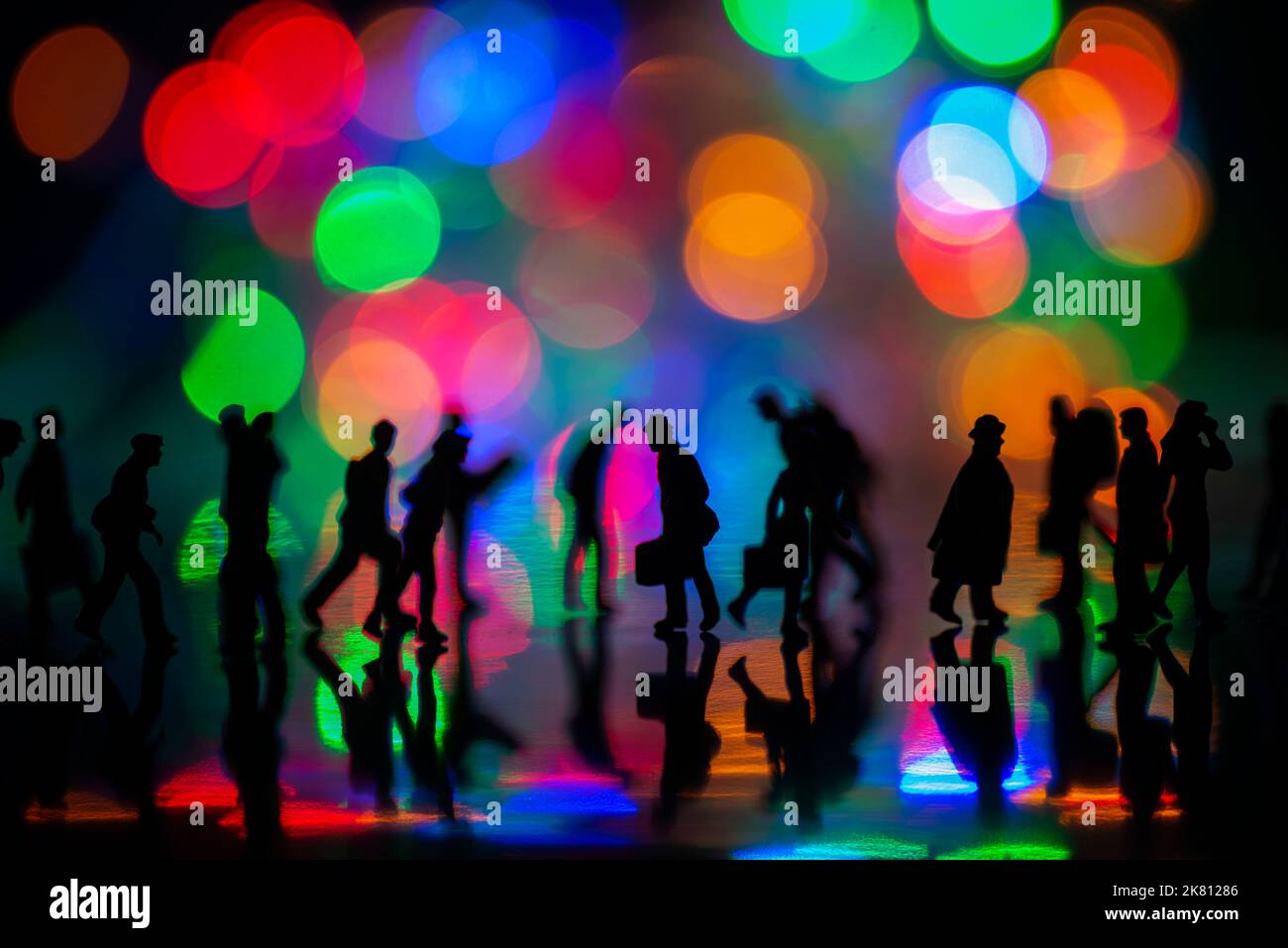 Miniature people toys studio set up - Silhouette side view of people busy walking with colorful blurred bokeh background. Focus at the man in the midd Stock Photo