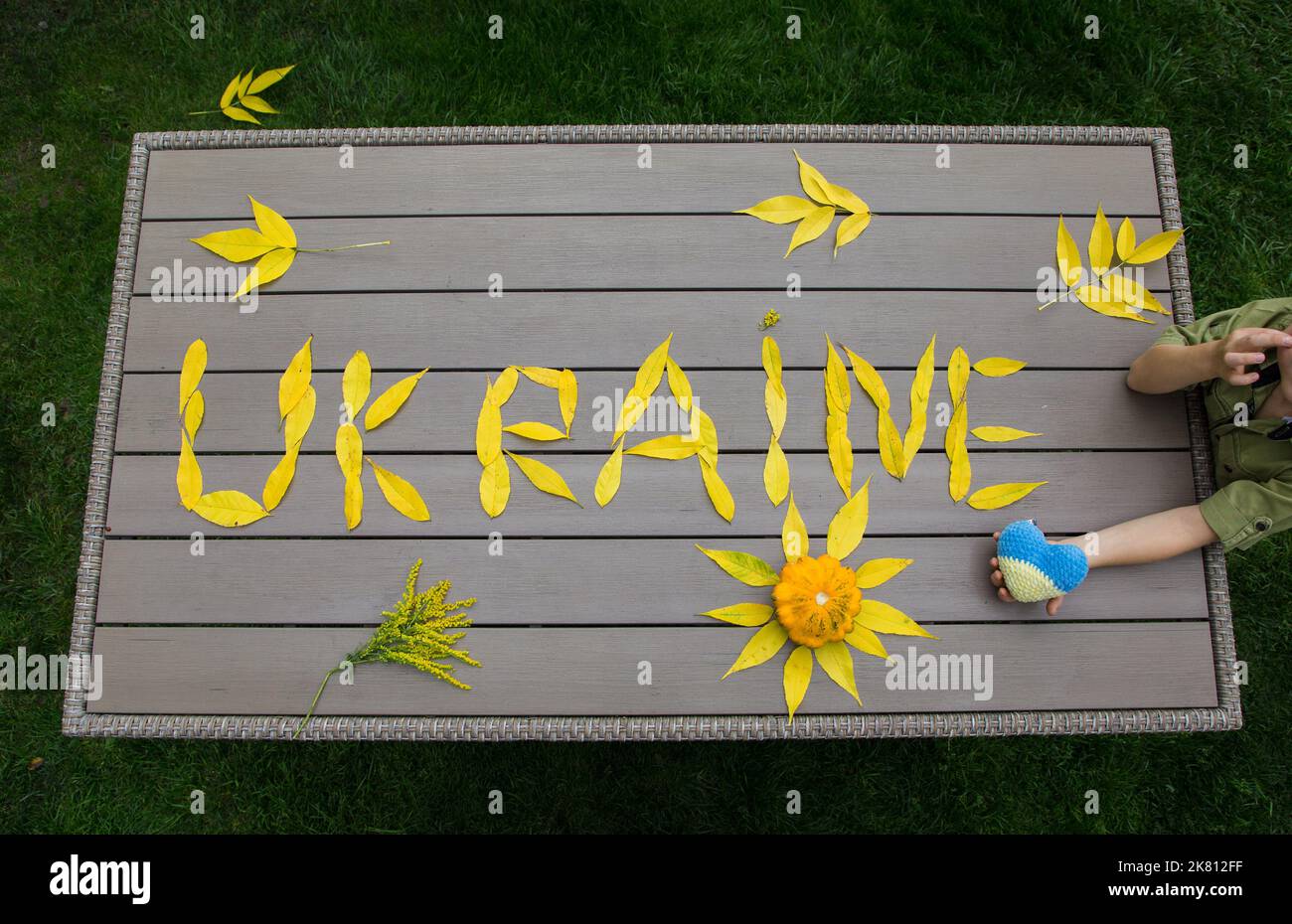 word Ukraine laid out on table of fallen yellow autumn leaves. Ukrainians want peace. Stop war. concept of supporting Ukrainian people, drawing attent Stock Photo