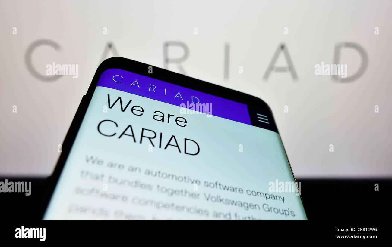 Mobile phone with website of German automotive software company Cariad SE on screen in front of business logo. Focus on top-left of phone display. Stock Photo