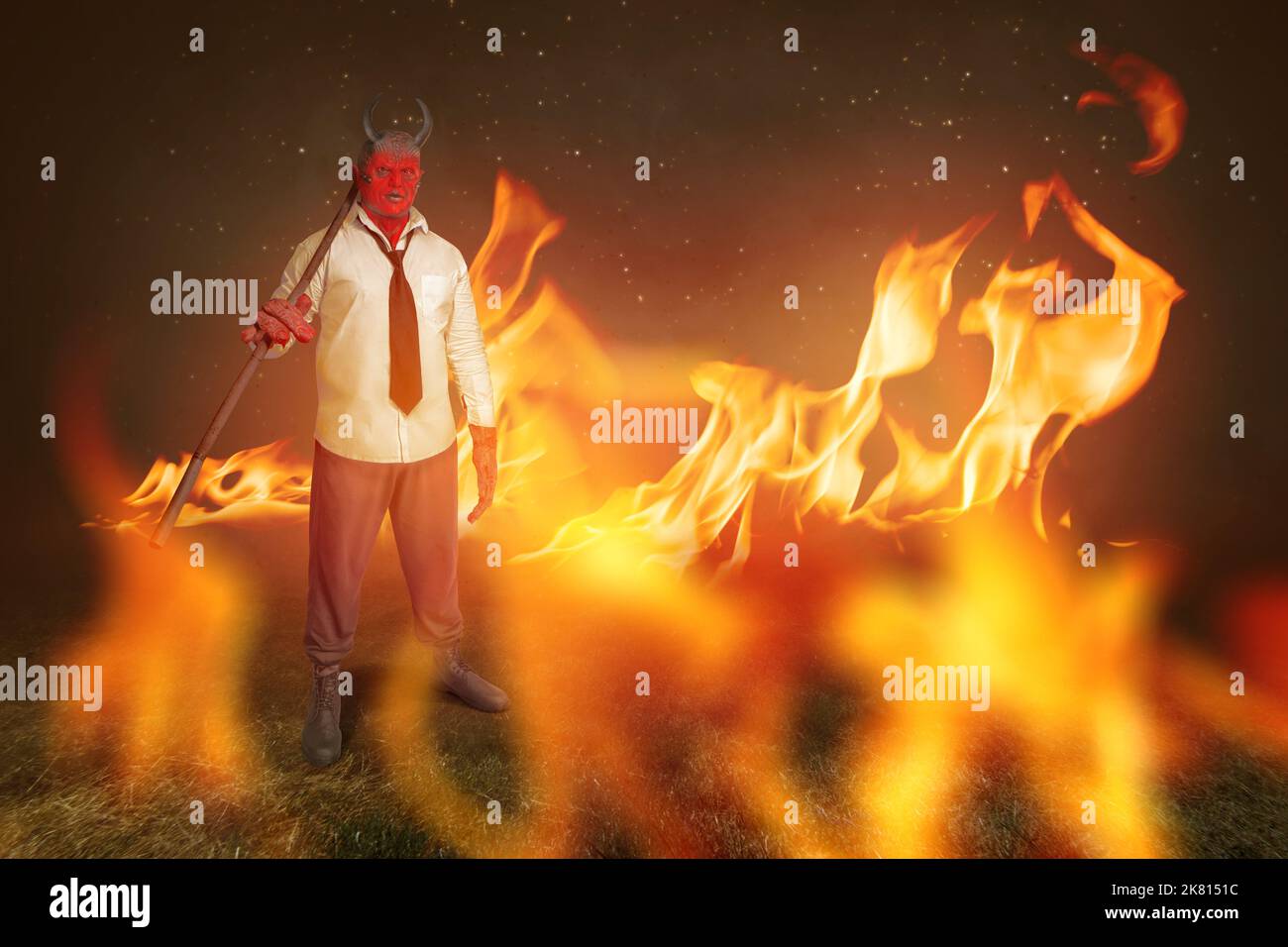 Devilman is standing while holding sticks with fire's background. Halloween concept Stock Photo