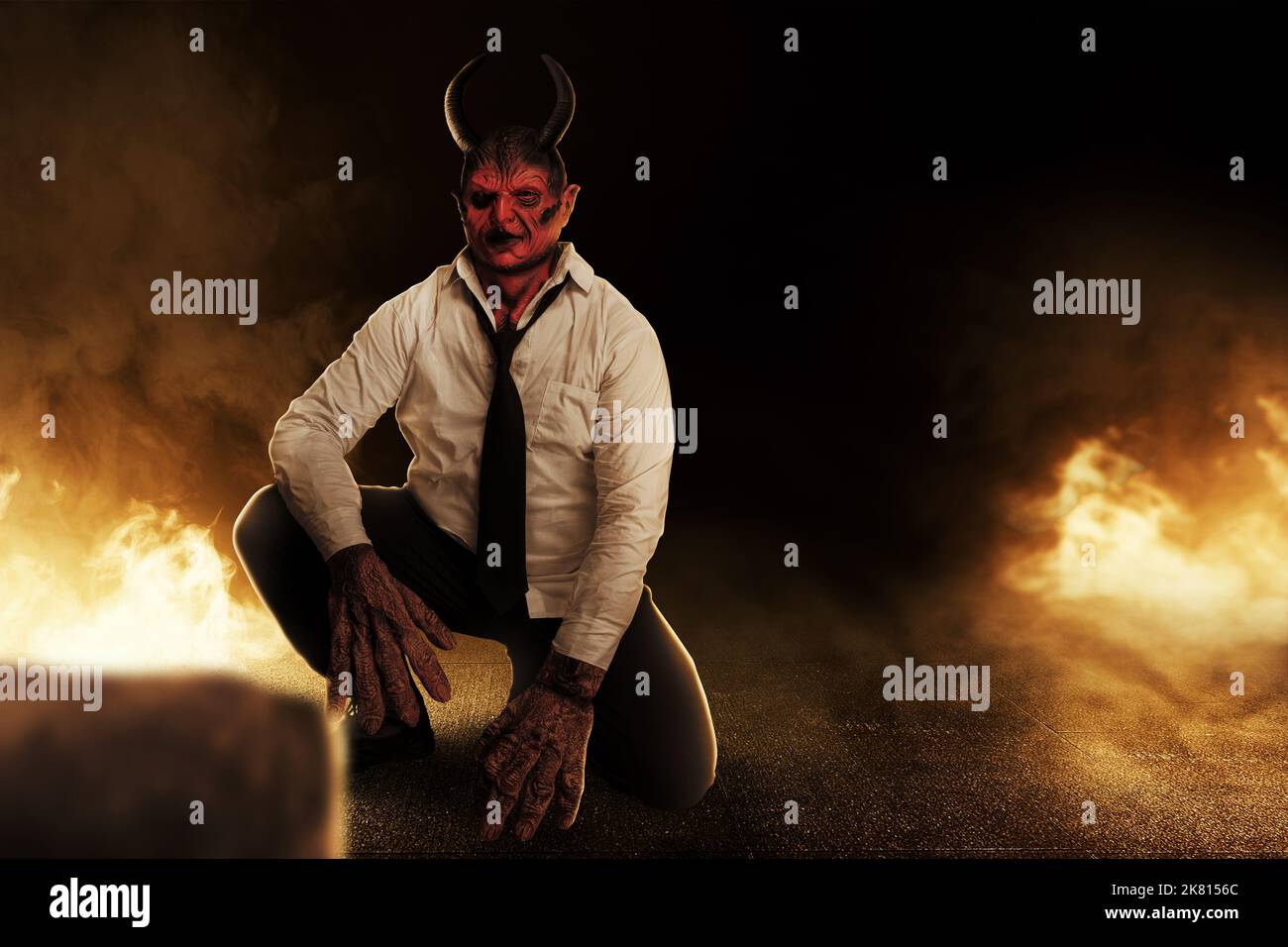 Devilman is sitting with the fire's background. Halloween concept Stock Photo