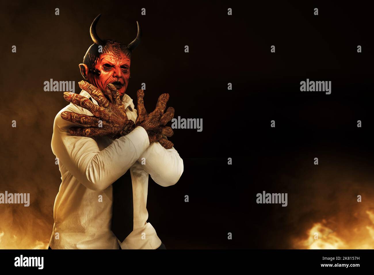 Devilman is standing in the fire's background. Halloween concept Stock Photo