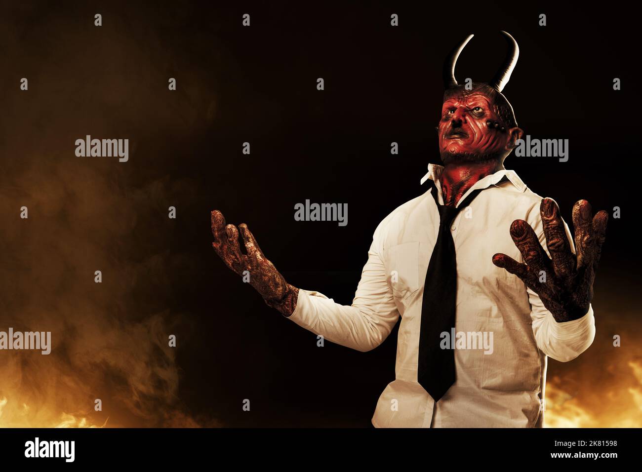 Devilman is standing in the fire's background. Halloween concept Stock Photo