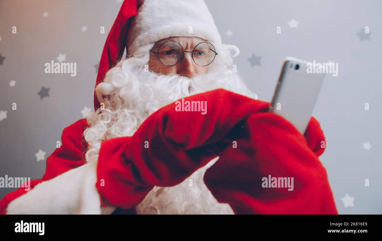 Serious guy in Santa outfit is using smartphone touching screen ...
