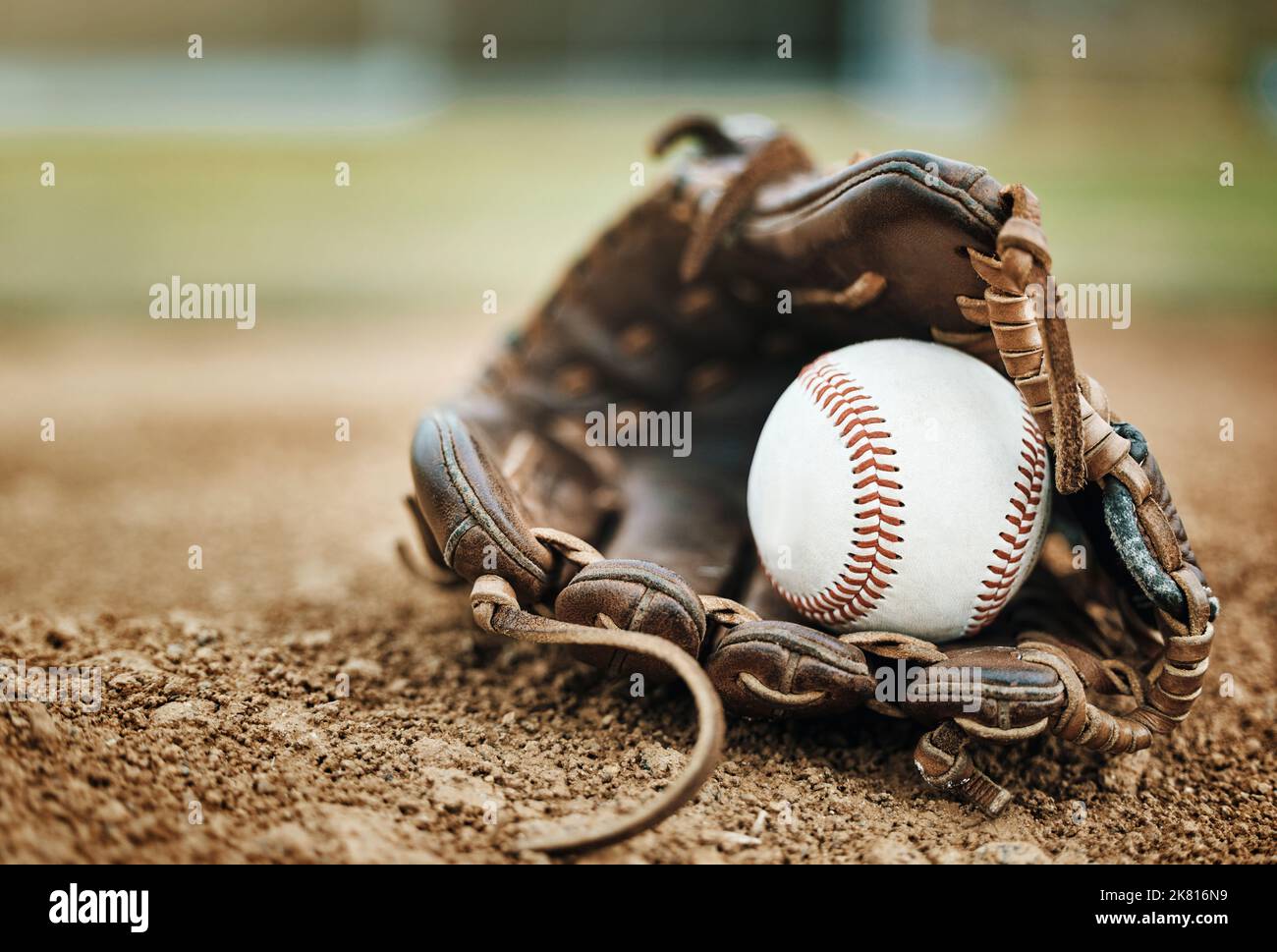 Baseball, leather glove and ball on pitch sand after fitness, workout or training for match or competition. Zoom, texture and softball mitt on field Stock Photo