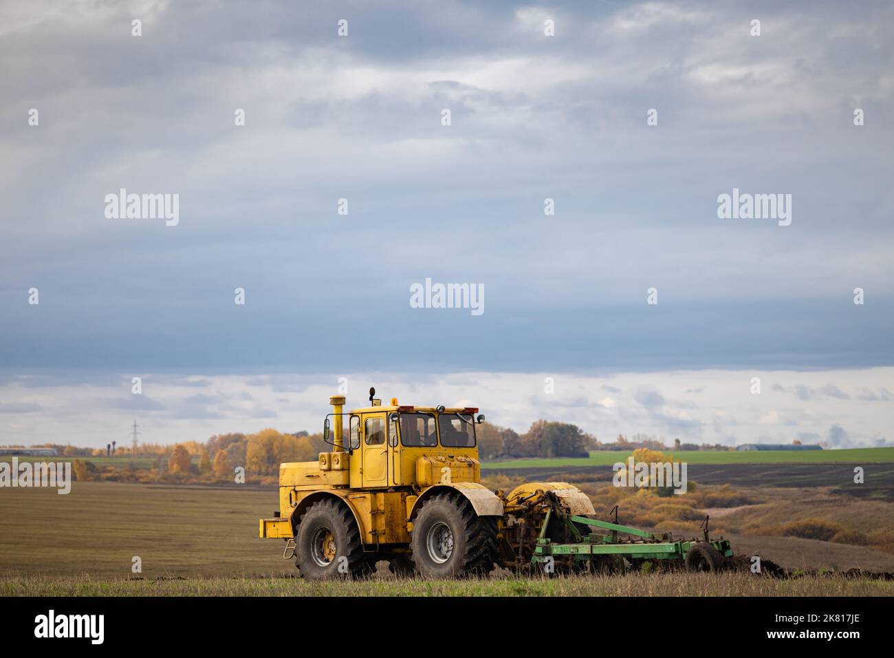 old model tractor working in the field. big tractor plows the ground