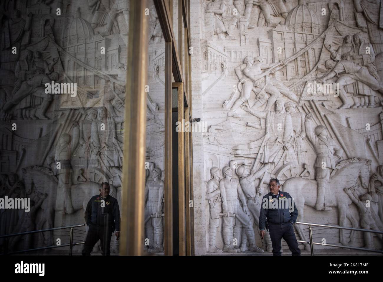 Rom, Italy. 19th Oct, 2022. An employee of a security company stands in front of the entrance of the Palazzo degli Uffici in front of a relief by artist Publio Morbiducci that shows, among others, former Italian dictator Mussolini sitting on a horse. (to dpa 'Ahead of 100th anniversary of the seizure of power by the fascists in Italy') Credit: Oliver Weiken/dpa/Alamy Live News Stock Photo
