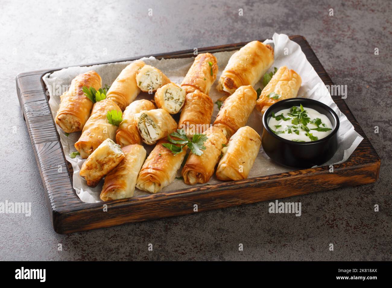 borek sigara boregi fried pastry wrapped in cheese in phyllo closeup on the wooden board on the table. Horizontal Stock Photo