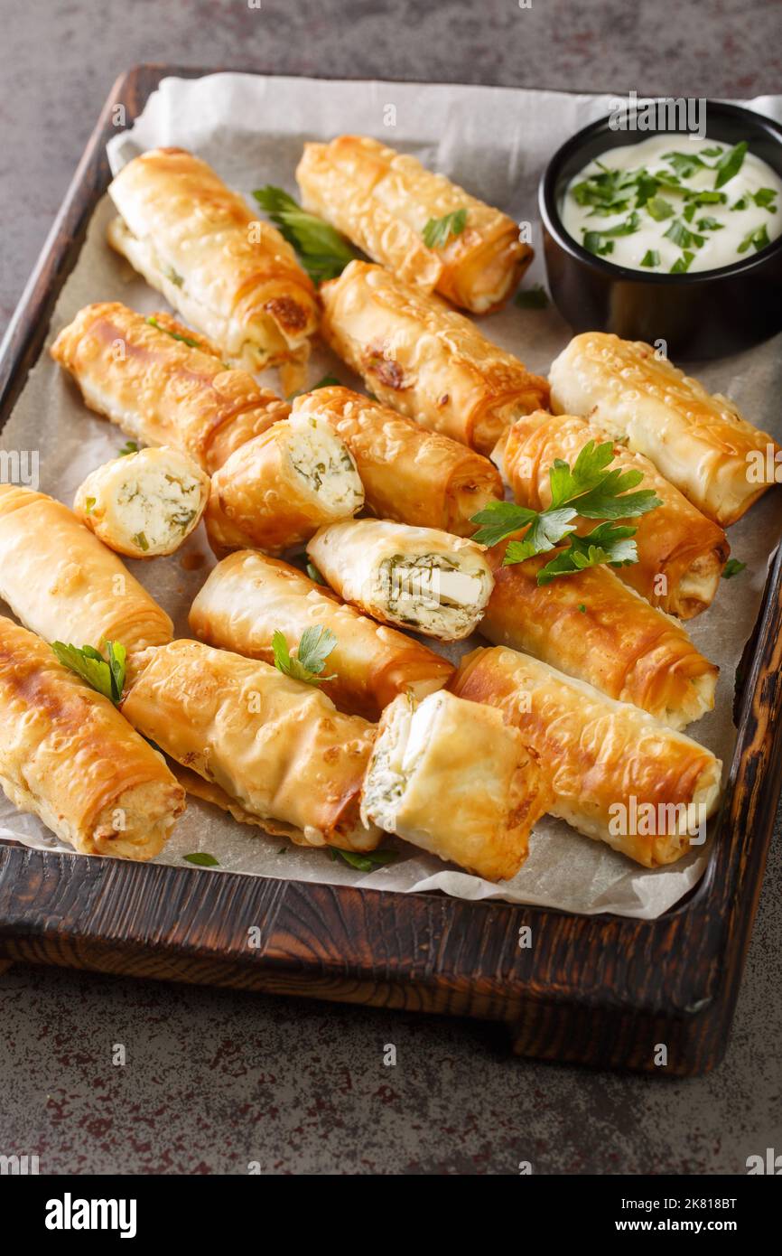 Sigara Boregi Turkish Cigar Shaped Rolls stuffed with cheese and herbs closeup on the wooden board on the table. Vertical Stock Photo