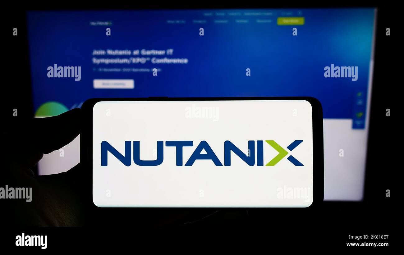 Person holding cellphone with logo of US cloud computing company Nutanix Inc. on screen in front of business webpage. Focus on phone display. Stock Photo