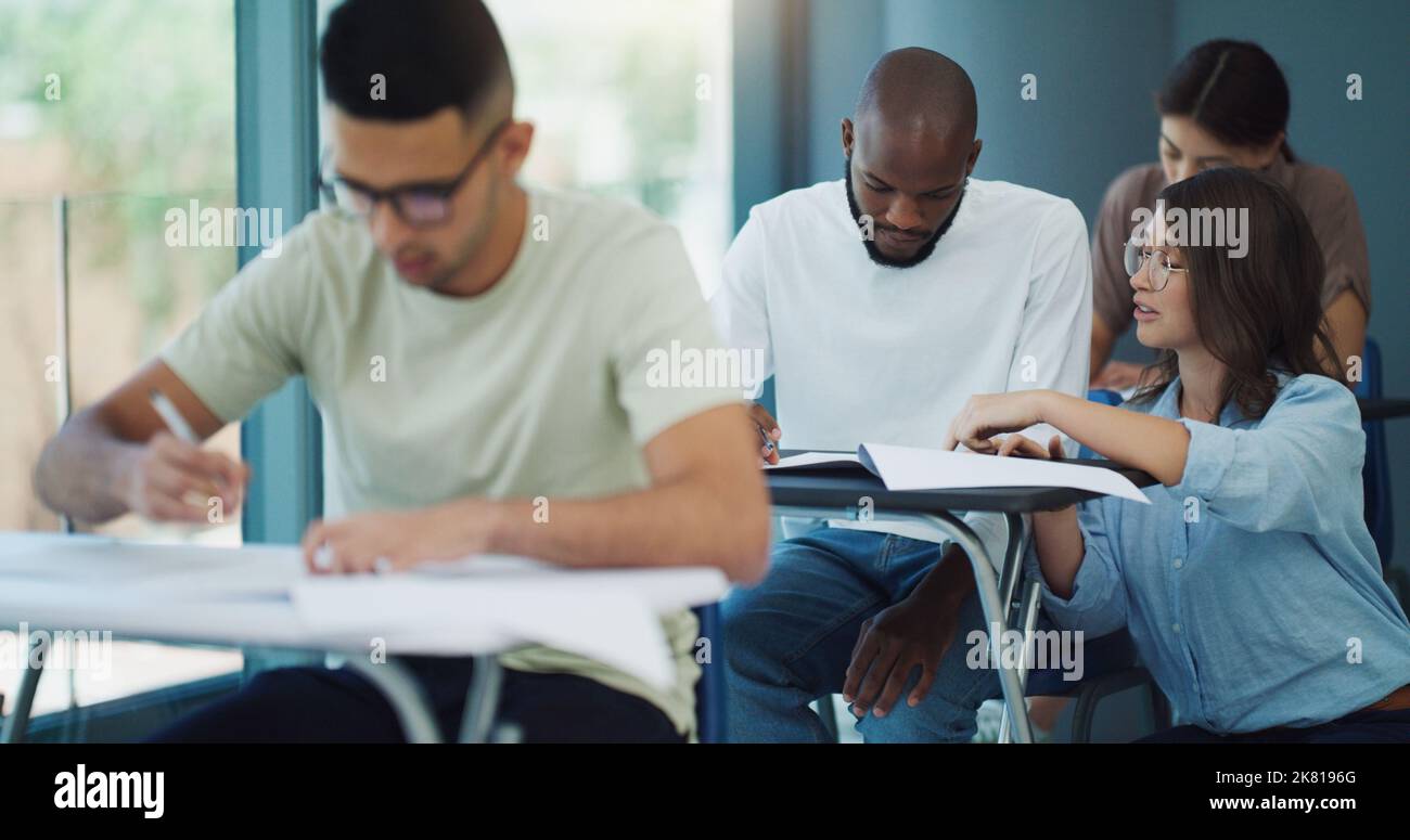 The noblest pleasure is the joy of understanding. a professor helping a student during an exam at university. Stock Photo