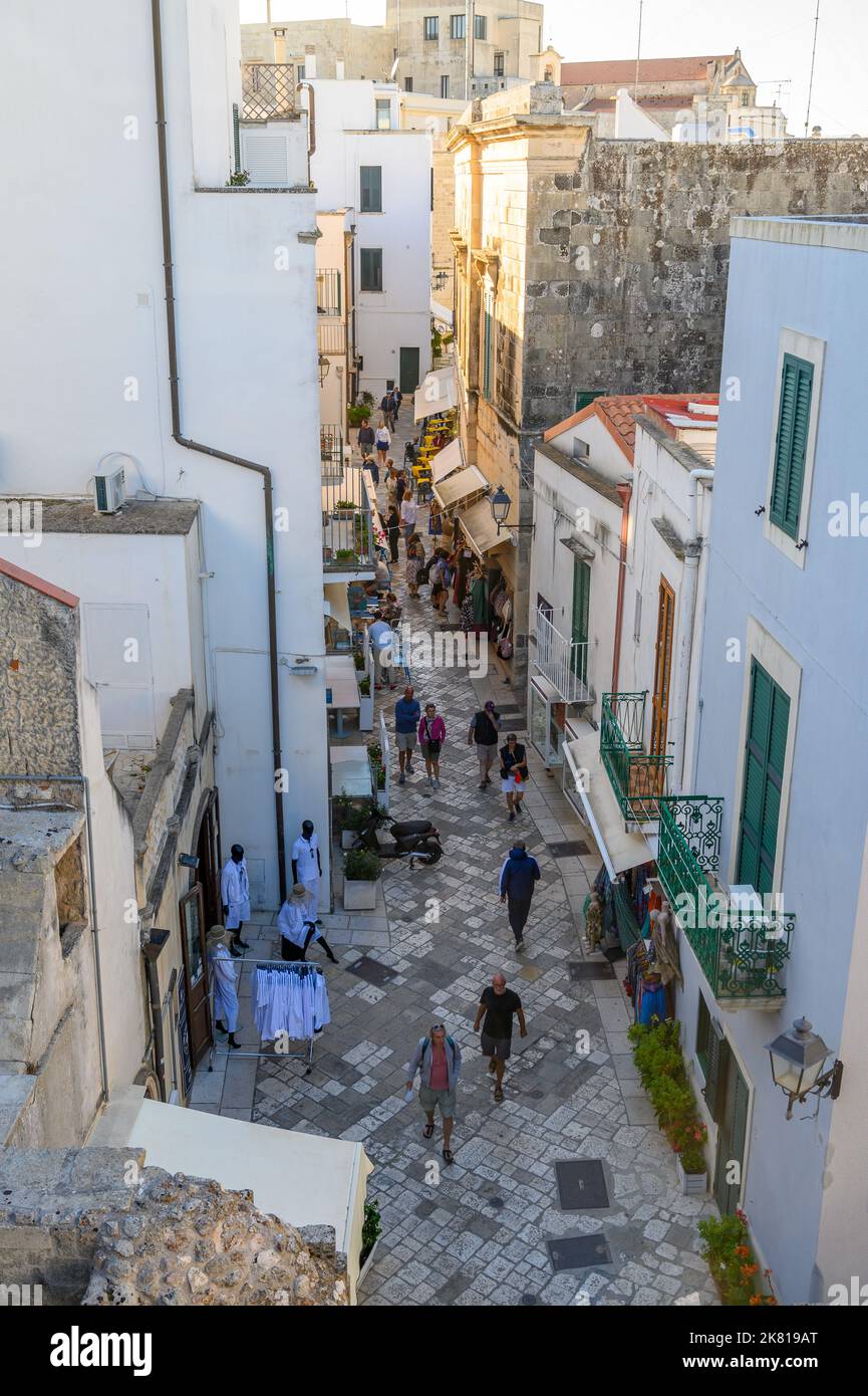Via Immacolata, a narrow, paved street in Otranto with small shops and restaurants and people walking seen from a height. Apulia (Puglia), Italy. Stock Photo