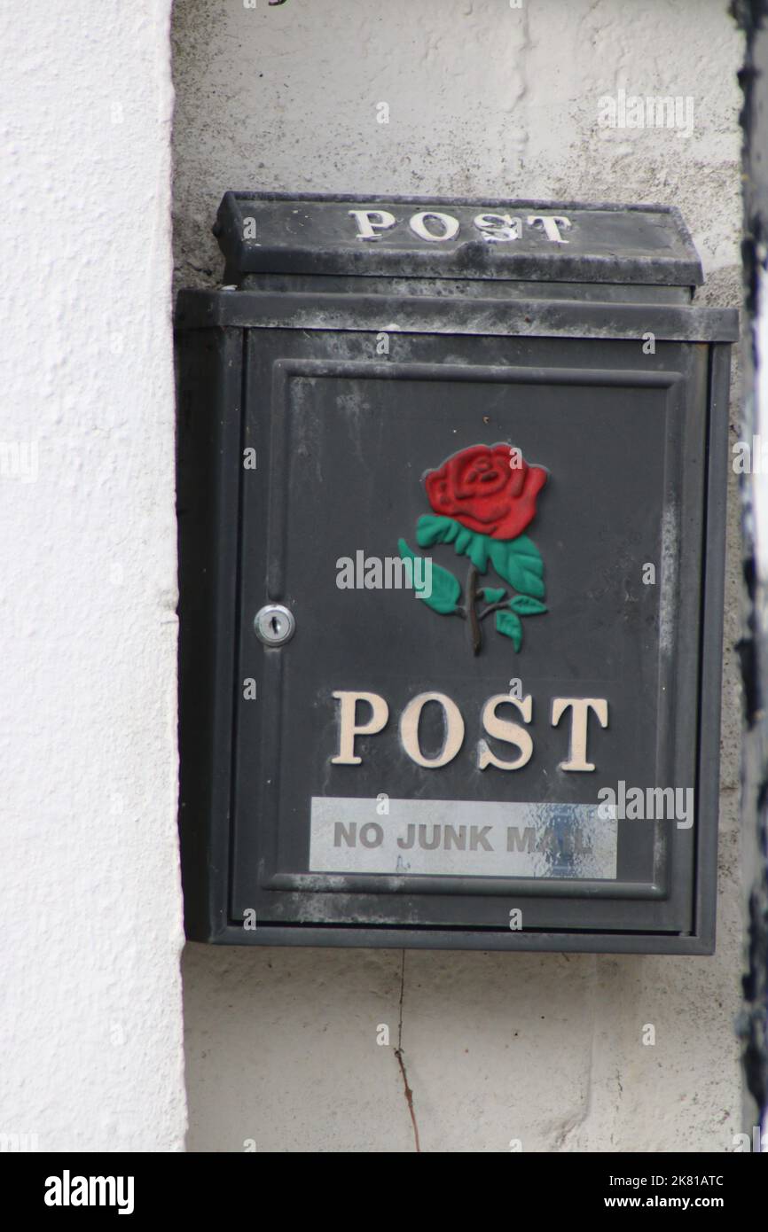 a-vertical-shot-of-a-post-box-with-a-red-rose-symbol-and-text-hanging