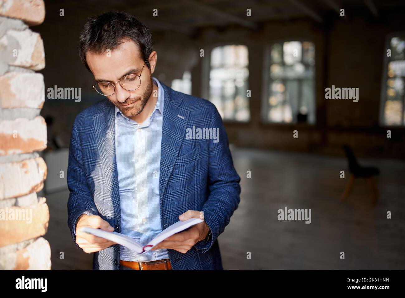 Portrait of businessman standing at the wall in empty room, making notes, working on new company opening Stock Photo