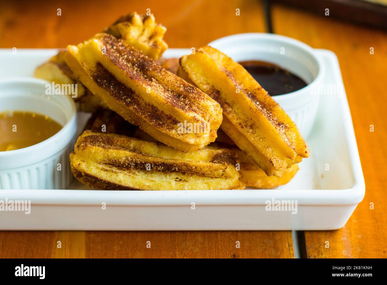 A dish of short churros with a caramel and chocolate dipping sauce in Cebu, Philippines Stock Photo