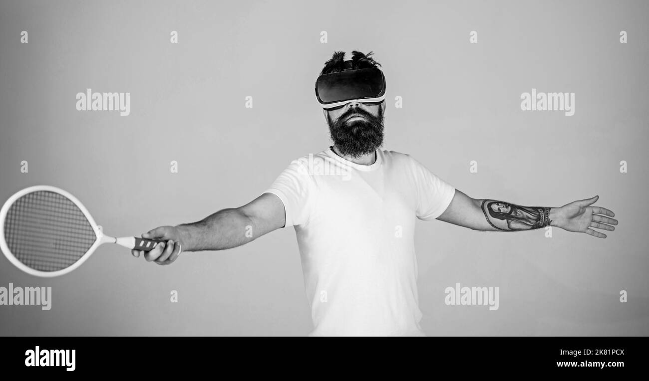 Guy with VR glasses play tennis with racket and ball. Man with beard in