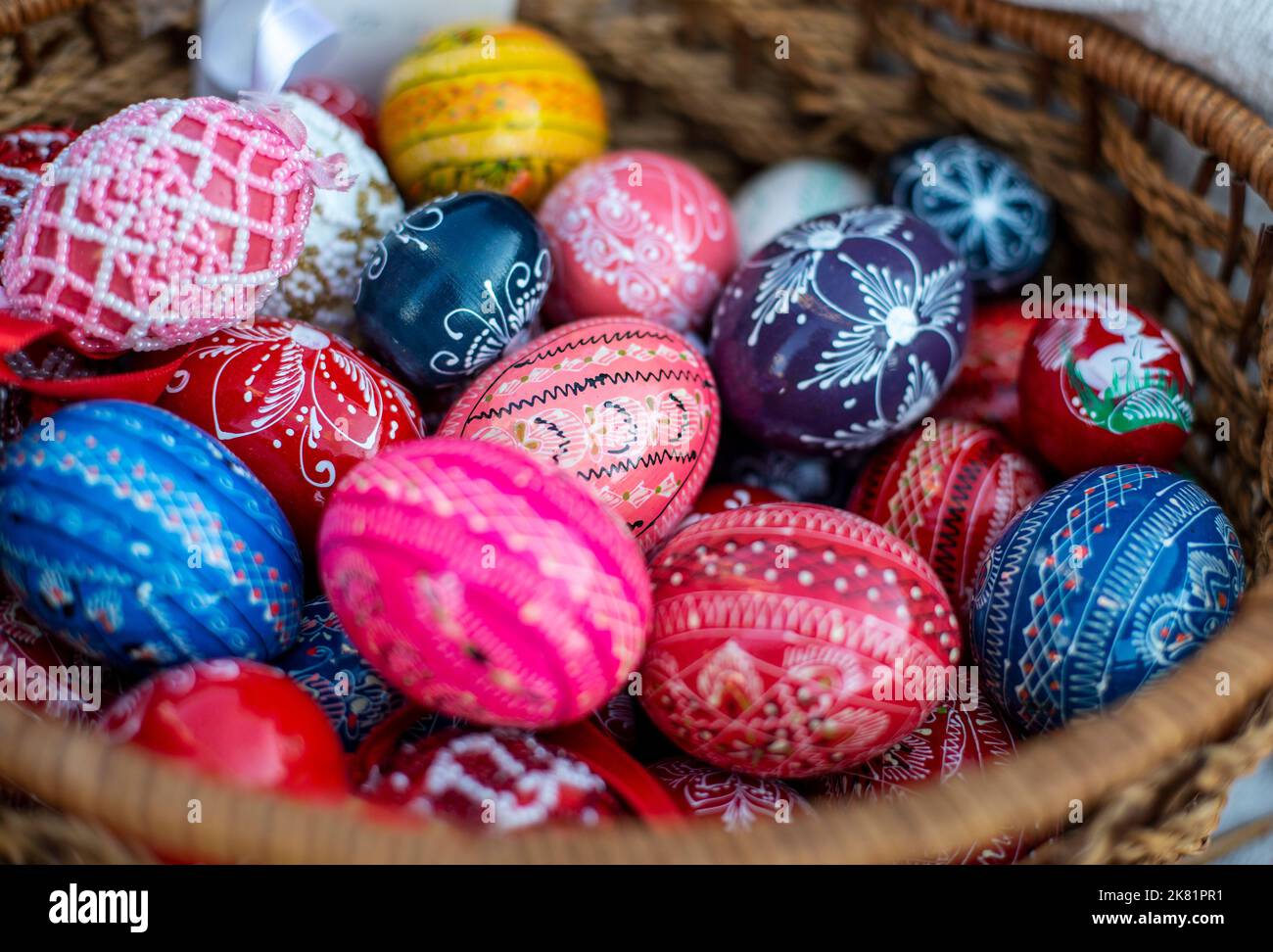 Many colorful decorated easter eggs in wicker basket Stock Photo