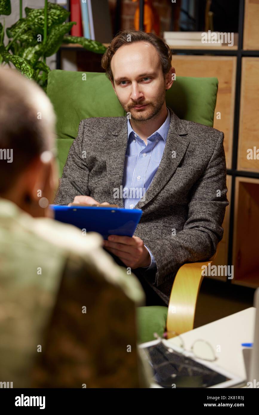 Two People Soldier In Military Uniform And Psychologist At Therapy Session In Office Indoors