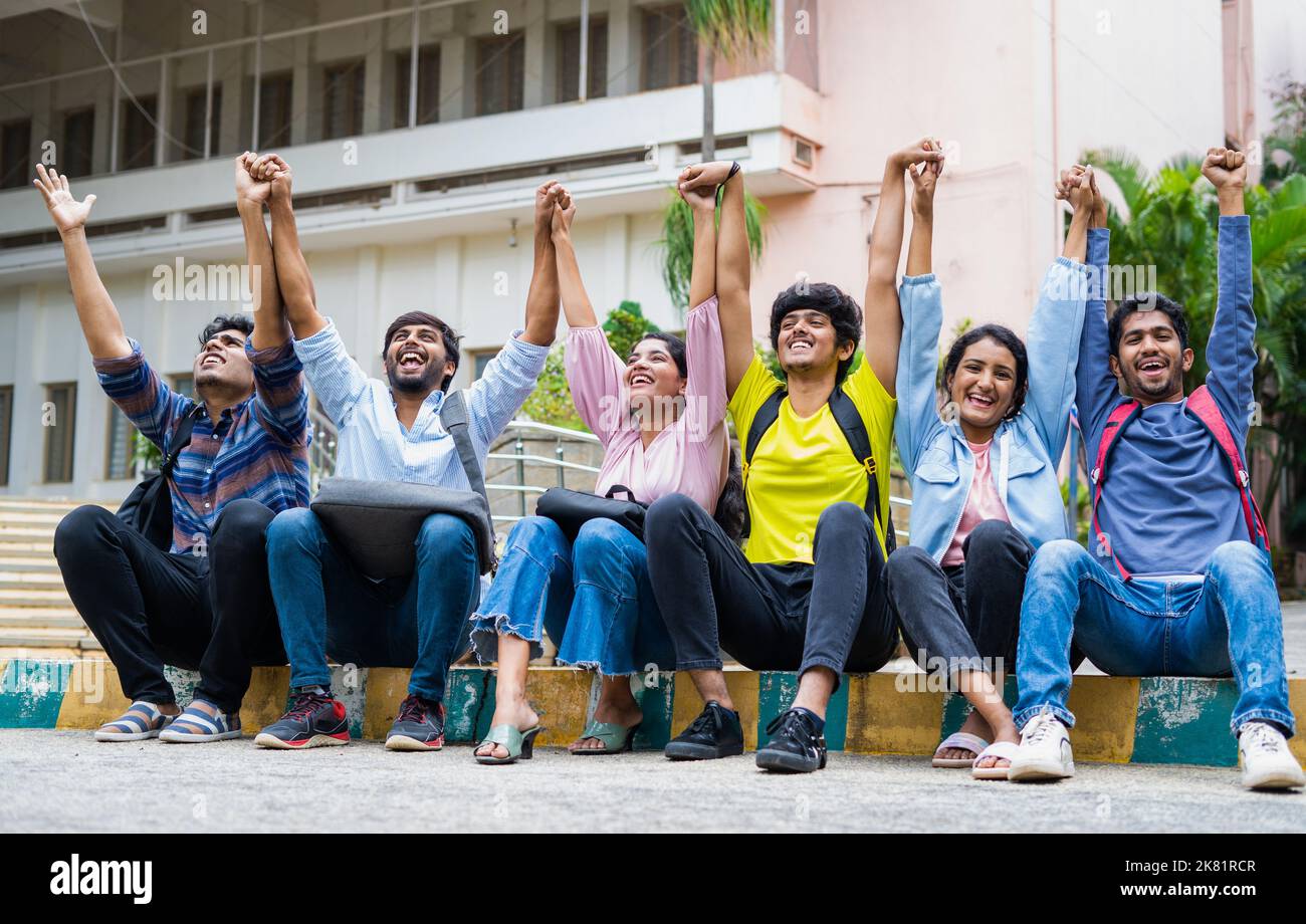 Excited group of students shouting by holding eachother hands after exams at on college campus - concept of friendship, bonding, happiness Stock Photo