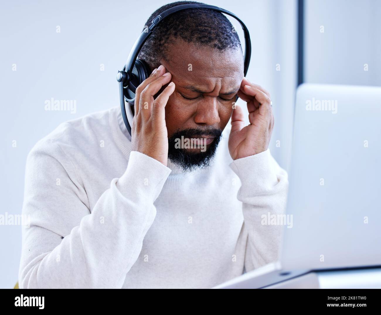 Someone save me from this gloomy day. a mature call centre agent looking stressed out while working in an office. Stock Photo