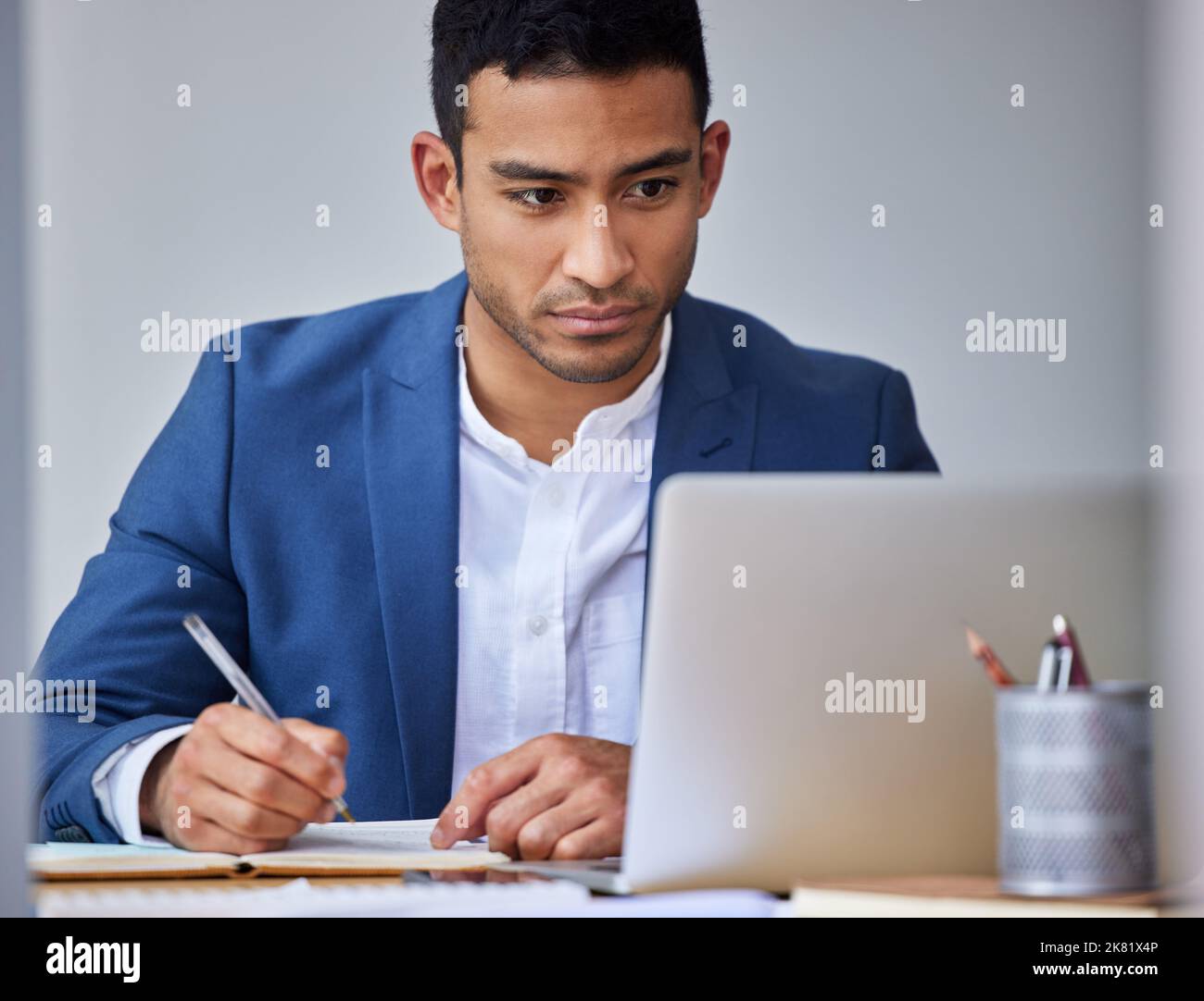 This presentation could make or break the business. a young businessman taking notes while using his laptop. Stock Photo