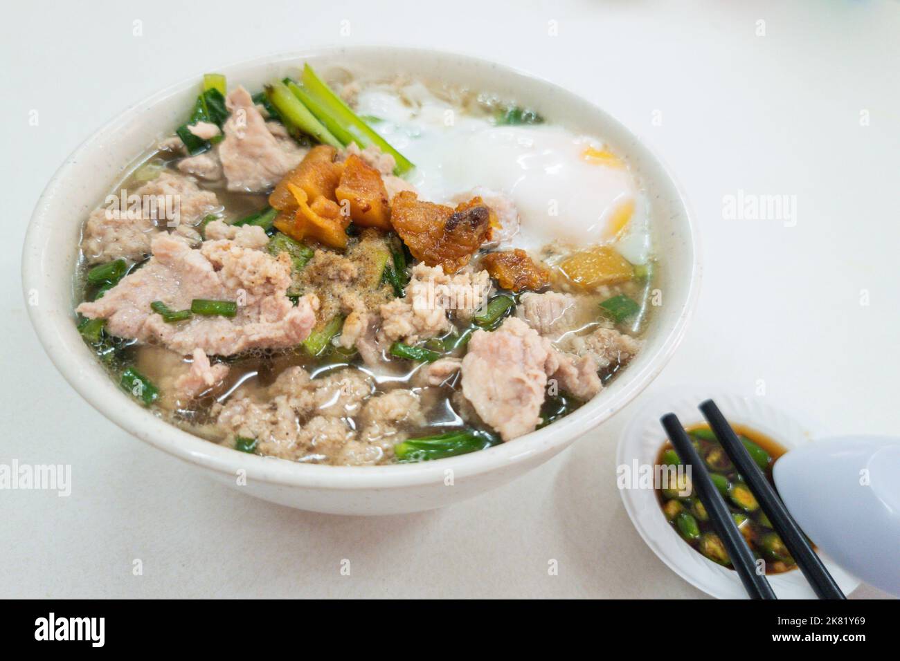 Simple Chinese pork noodle soup with eggs served with lard and chili