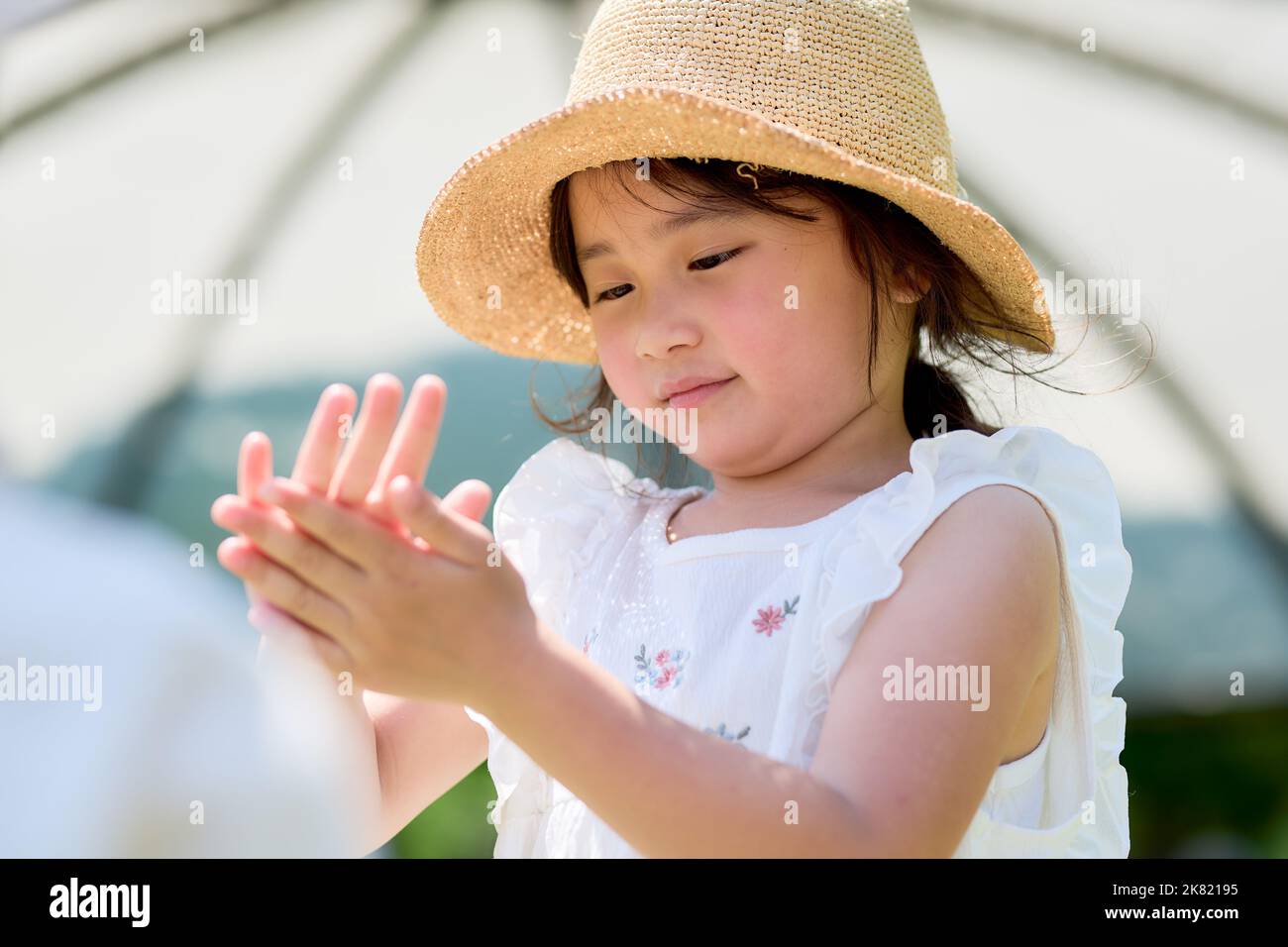 Japanese kid using hand sanitizer at a city park Stock Photo