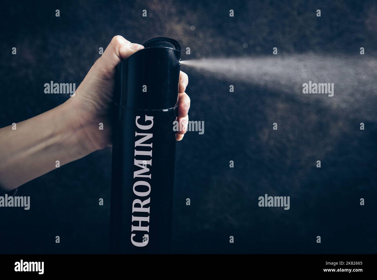 Conceptual image of chroming. Process of getting high using household chemicals to inhale. Child hand holding hairspray bottle and spray aerosol. Stock Photo