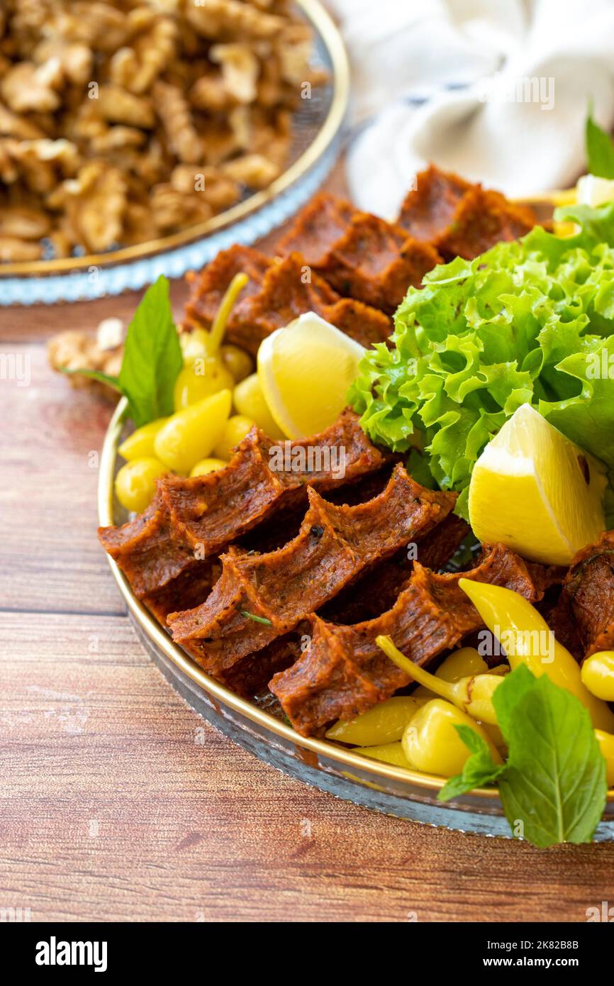 Cig kofte or raw meatballs on wood background. Traditional Turkish cuisine delicacies. Close-up. Stock Photo