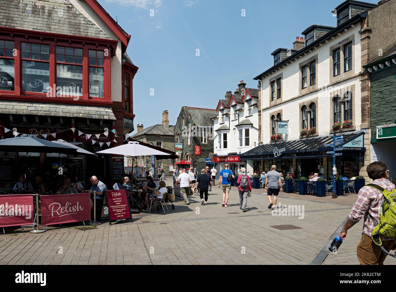 People tourists visitors walkers eating drinking at restaurants cafe and shops in the town centre in summer Main Street Keswick Cumbria England UK Stock Photo