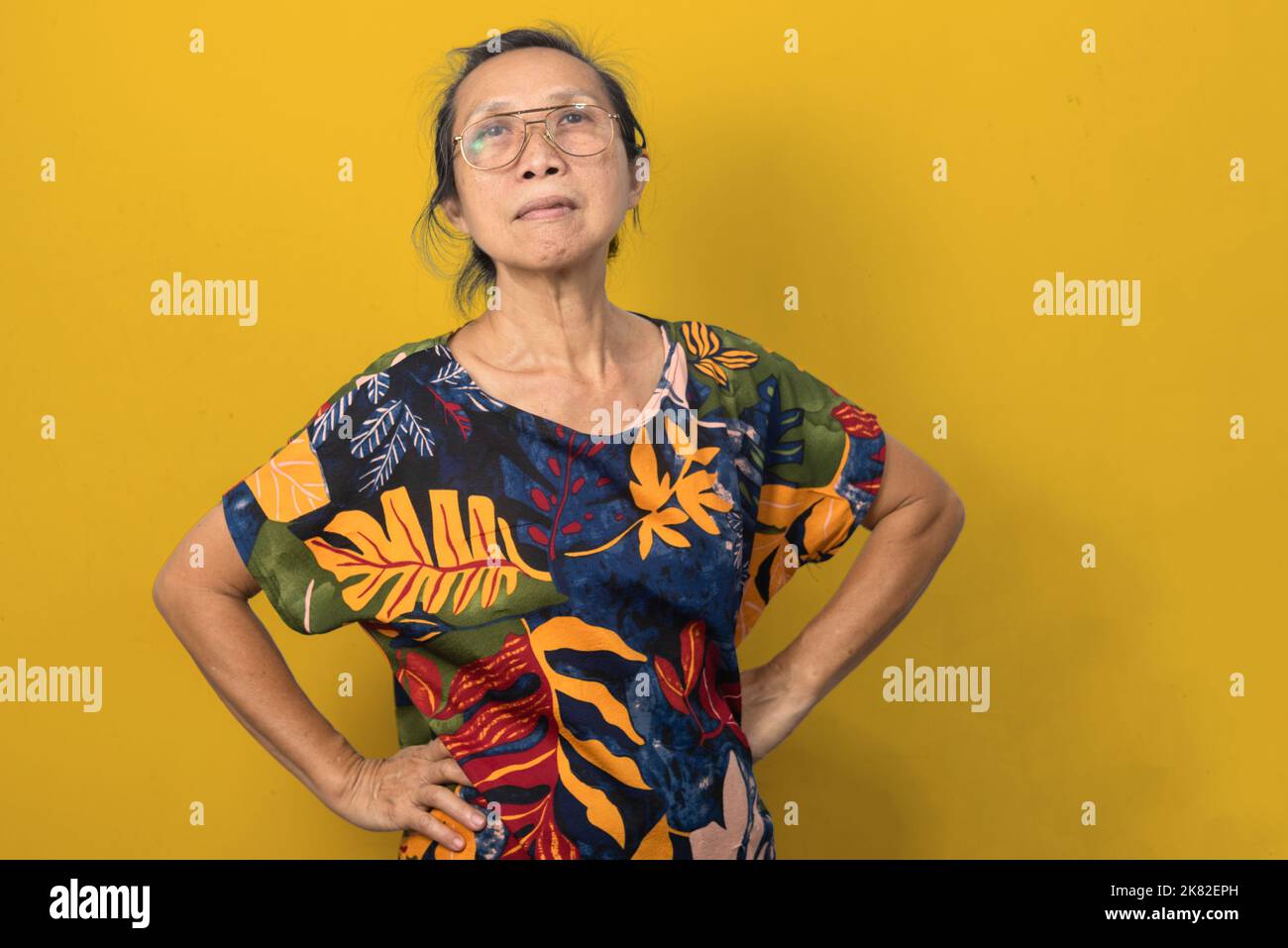 Asian elderly woman standing at her waist on a yellow background. Stock Photo