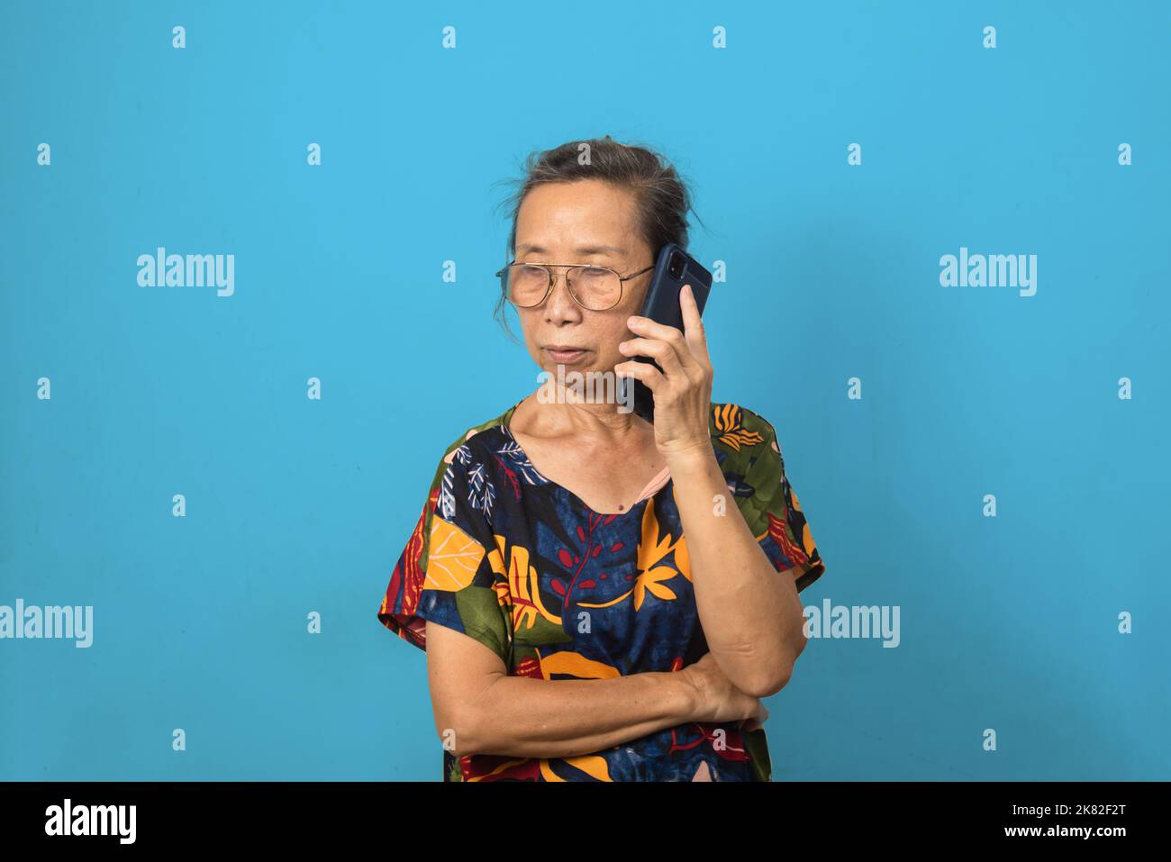 Elderly woman using mobile smartphone technology communications on background. Stock Photo