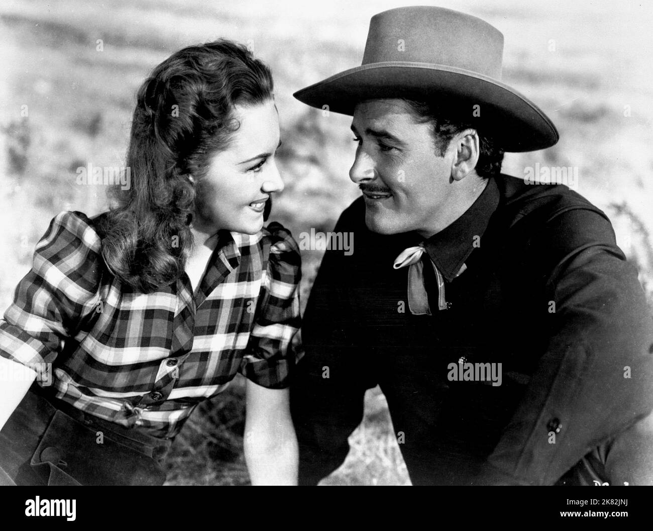 Olivia De Havilland & Errol Flynn Film: Dodge City (USA 1939) Characters: Abbie Irving & Wade Hatton  Director: Michael Curtiz 01 April 1939   **WARNING** This Photograph is for editorial use only and is the copyright of WARNER BROS. and/or the Photographer assigned by the Film or Production Company and can only be reproduced by publications in conjunction with the promotion of the above Film. A Mandatory Credit To WARNER BROS. is required. The Photographer should also be credited when known. No commercial use can be granted without written authority from the Film Company. Stock Photo