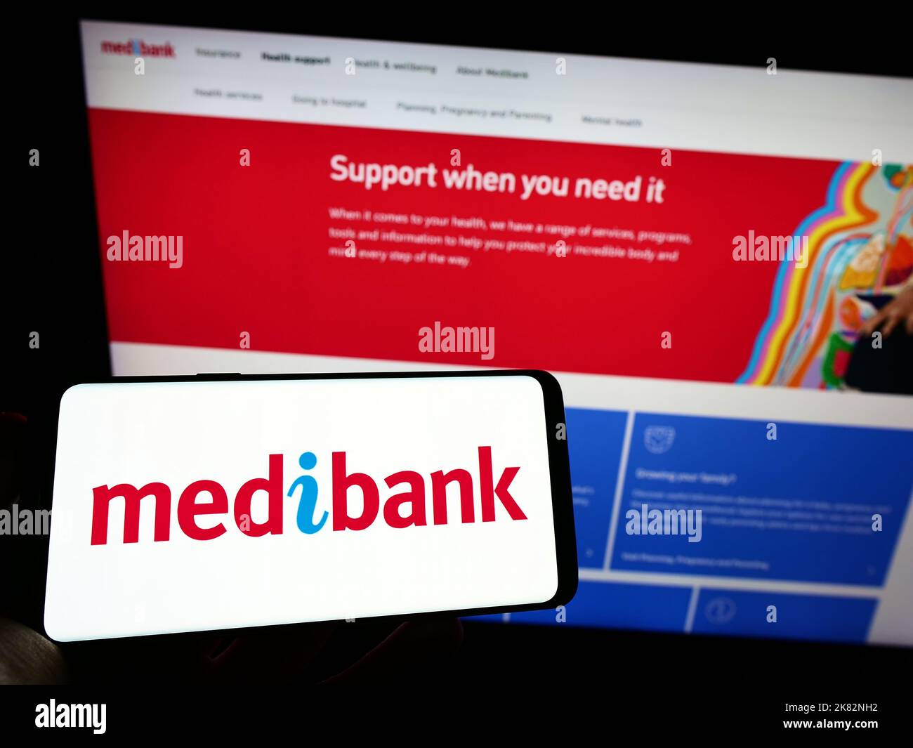 Person holding smartphone with logo of health insurance company Medibank Private Limited on screen in front of website. Focus on phone display. Stock Photo