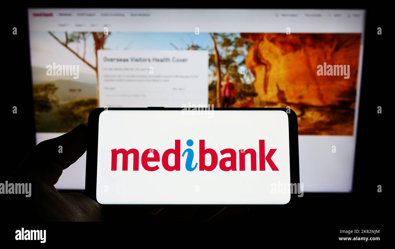 Person holding cellphone with logo of health insurance company Medibank Private Limited on screen in front of web page. Focus on phone display. Stock Photo