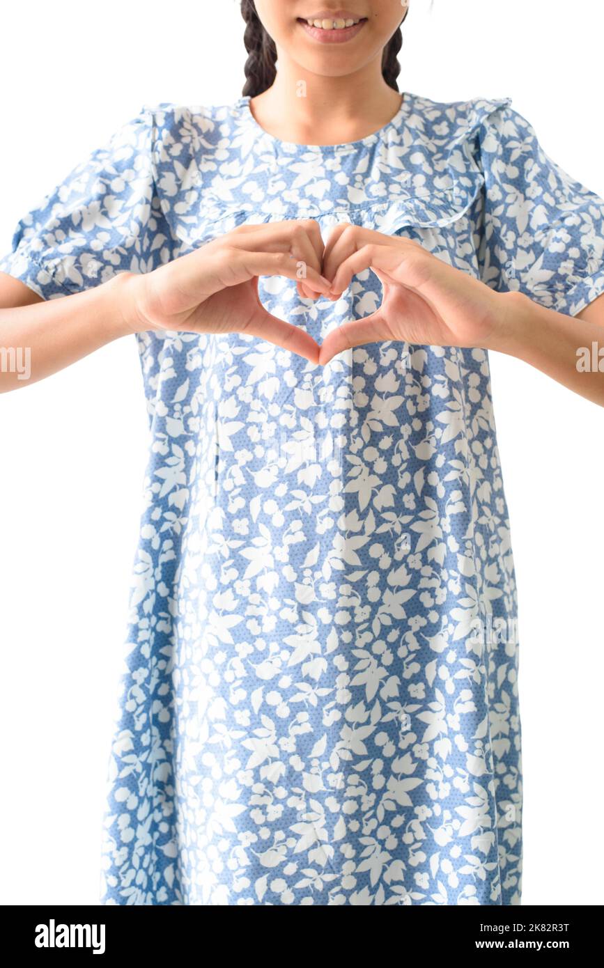 A little girls is making a heart sign with her hands on a white background Stock Photo