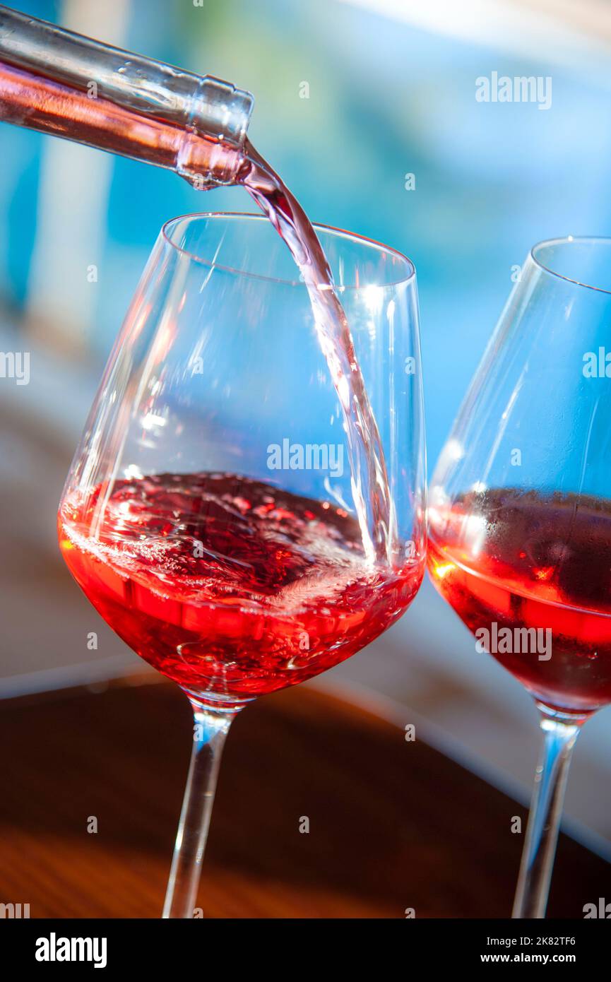 ROSÉ WINE Pouring fresh glasses of rosé wine in sunny sparkling sunlit alfresco luxury holiday vacation, summer infinity pool terrace resort Stock Photo